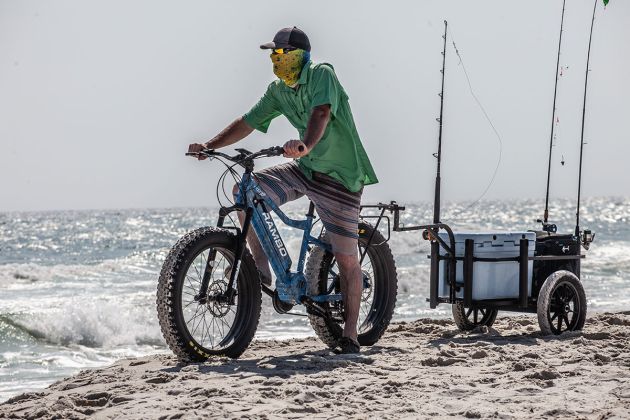 Man riding Rambo eBike pulling trailer on beach to go ocean fishing