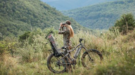 Woman using binoculars to scout for game while hunting with Rambo e-Bike.